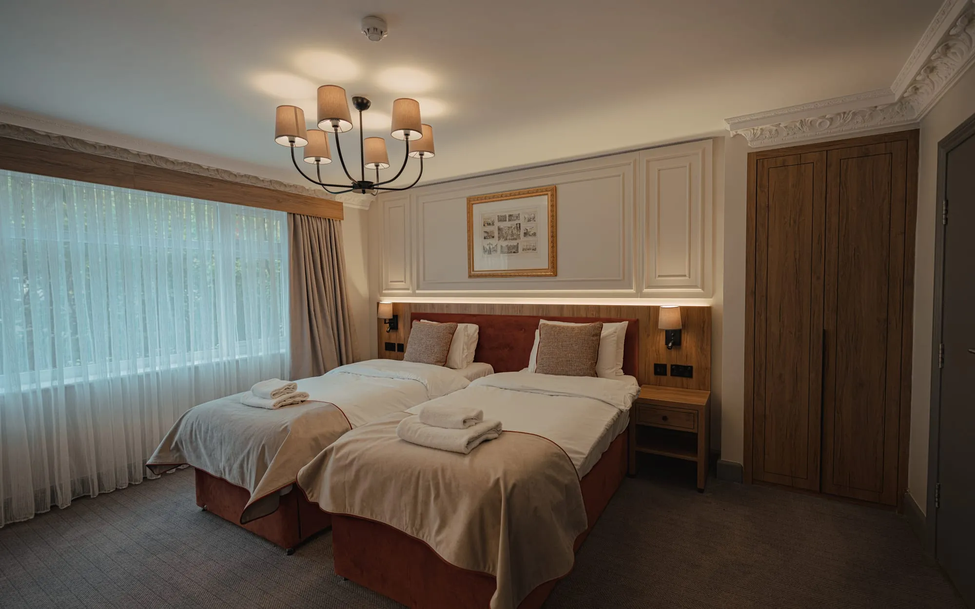 Superior Twin with twin beds under a chandelier, a framed print and a wide window
