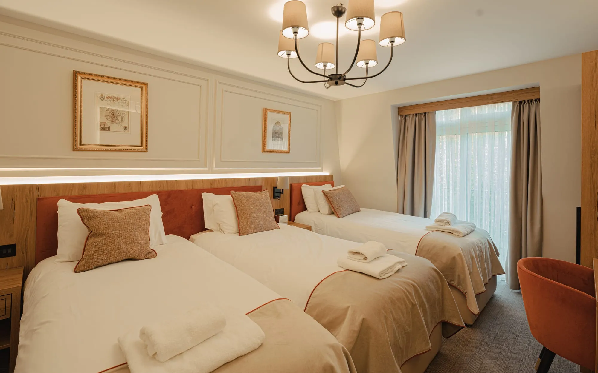 Triple room with three single beds, panelled walls and a chandelier